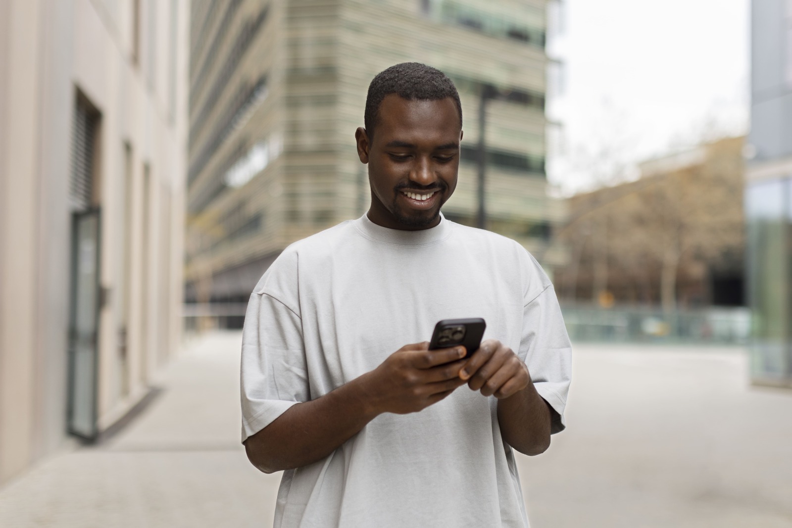 Homem sentado no banco da praça olhando para o celular. 